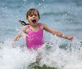 Image showing Little girl laughing and crying in the spray of waves