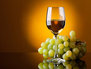 Image showing A glass of white wine and a bunch of green grapes