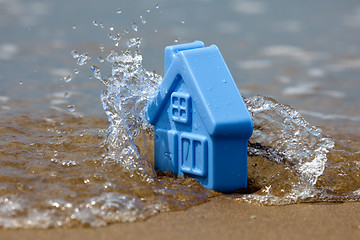 Image showing Toy plastic house on the sand washes wave