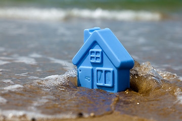 Image showing Toy plastic house on the sand washes wave