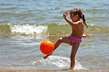 Image showing The little girl on the beach hit the ball