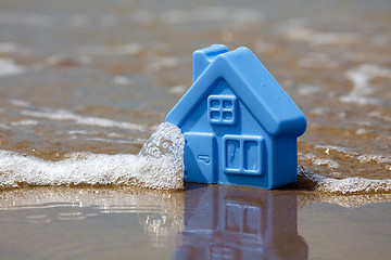 Image showing Toy plastic house on the sand washes wave