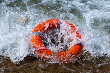 Image showing Red lifebuoy in the foam of the waves