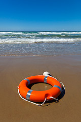 Image showing Red lifebuoy lying on the sand on the beach