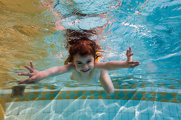 Image showing The girl smiles, swimming under water in the pool