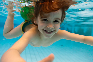 Image showing The girl smiles, swimming under water in the pool