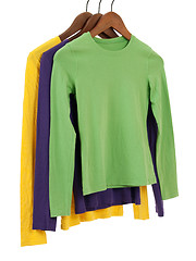 Image showing Three long sleeved shirts on wooden hangers