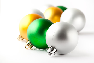 Image showing Green, gold and silver Christmas baubles on white