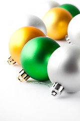 Image showing Green, gold and silver Christmas baubles on white