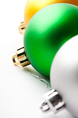 Image showing Green, gold and silver Christmas baubles on white