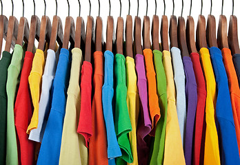 Image showing Variety of multicolored clothes on wooden hangers