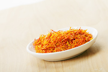 Image showing Saffron leaves spice in saucer on wood