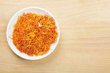 Image showing Saffron leaves spice in saucer on wood above view