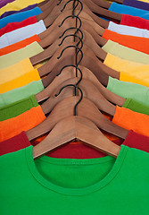 Image showing Many vibrant t-shirts on wooden hangers
