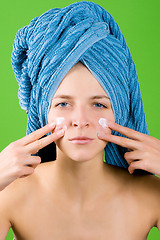 Image showing woman in blue towel applying facial cream