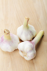 Image showing Three garlic bulbs on wood