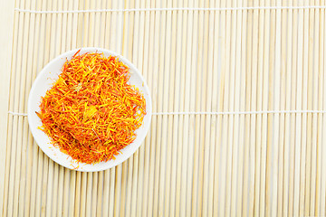 Image showing Saffron leaves spice in saucer on mat above view