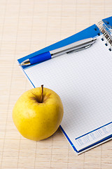 Image showing Open notebook, yellow apple and pencil 