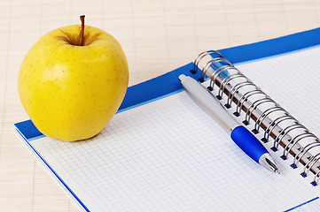 Image showing Open notebook, yellow apple and pencil 