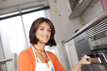 Image showing Woman opening the kitchen oven