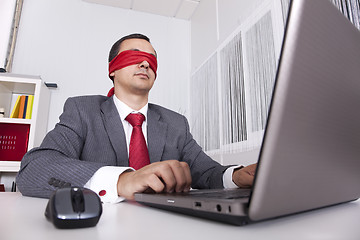 Image showing Blindfold businessman working with his laptop