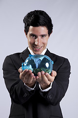 Image showing Businessman holding a piggybank full of coins