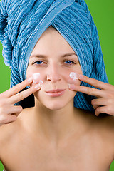 Image showing woman in blue towel applying facial cream