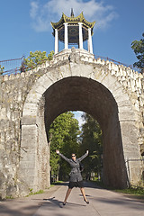 Image showing young women jump under arch in the park