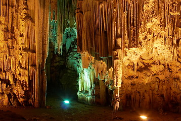 Image showing Young woman touching huge stalactites in colorful Melidoni Cave