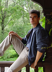 Image showing Relaxed young man sitting at wood