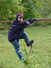 Image showing Young Boy climbing a fence