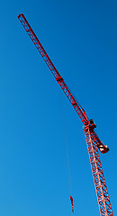 Image showing red construction tower crane with blue sky