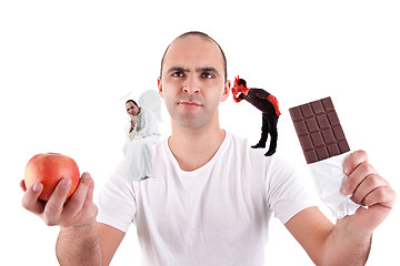 Image showing young man torn between eating an apple and a chocolate,between the devil and angel,
