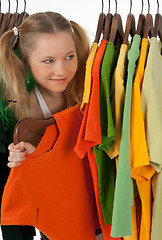 Image showing Curious girl looking out of the clothes rack