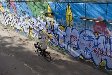 Image showing Cyclist riding along graffiti