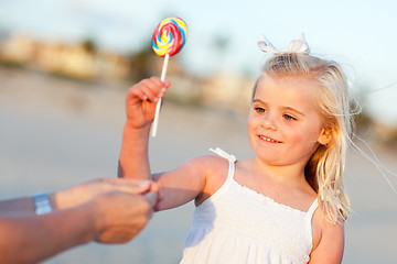 Image showing Adorable Little Girl Picking out Lollipop Outside