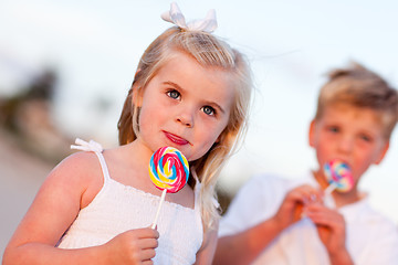 Image showing Cute Little Girl and Brother Enjoying Their Lollipops