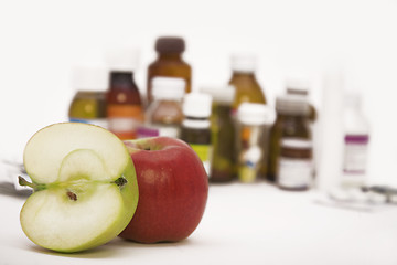 Image showing green and red apples in front of many pills and pill