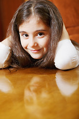 Image showing Cute brunette girl sitting at table