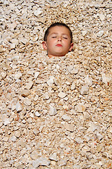 Image showing boy buried in the pebbles on the beach