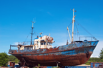 Image showing Old, rusty fishing launch on building berths in port 