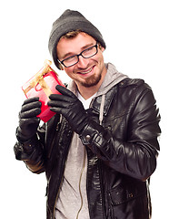 Image showing Warmly Dressed Young Man Holding Wrapped Gift To His Ear