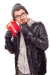 Image showing Warmly Dressed Young Man Holding Wrapped Gift To His Ear