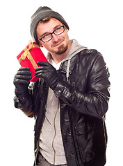 Image showing Warmly Dressed Young Man Holding Wrapped Gift To His Ear