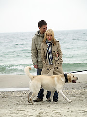 Image showing Mid aged couple with dog on sea shore