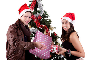 Image showing happy young couple, opening gifts beside Christmas tree