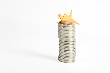 Image showing stack of silver coins and yellow origami bird