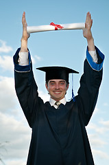 Image showing graduate with diploma in hands over head
