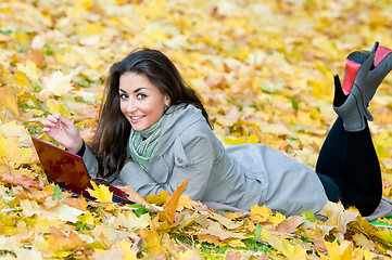 Image showing Happy student girl lying in autumn leaves with netbook