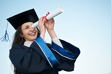 Image showing happy graduate girl looking through diploma